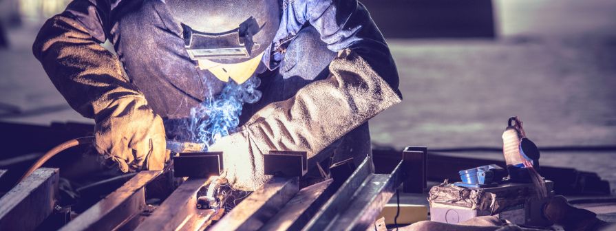 Factory worker hand welding steel